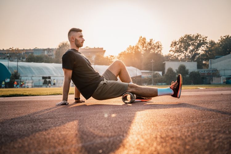 A man outside using a foam roller on his legs