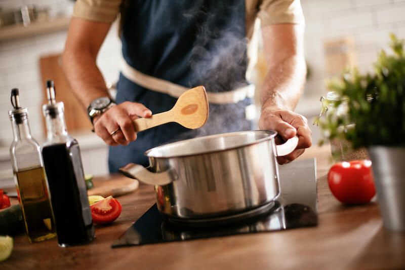 close up of saucepan with steam coming out and man stood behind