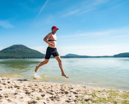 Man running along the sea shore wearing a heart rate monitor