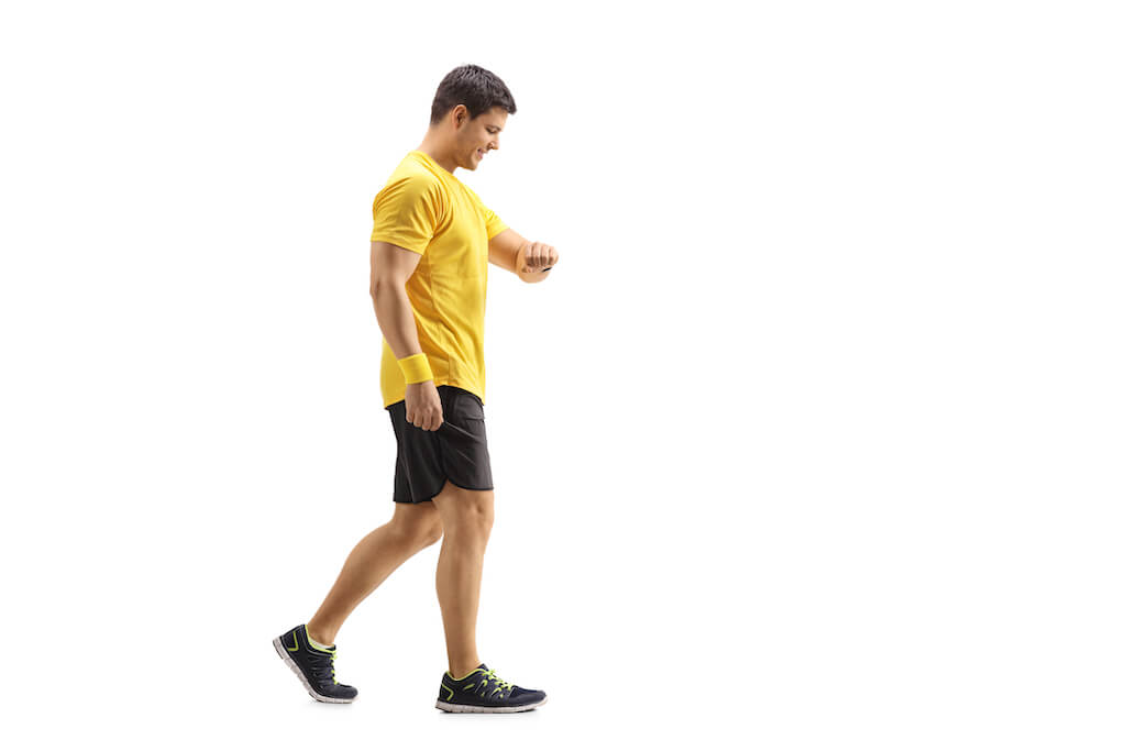 Man walking and checking his watch against white background, learning how to walk to lose weight