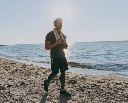 Happy man walks along beach on a sunny day