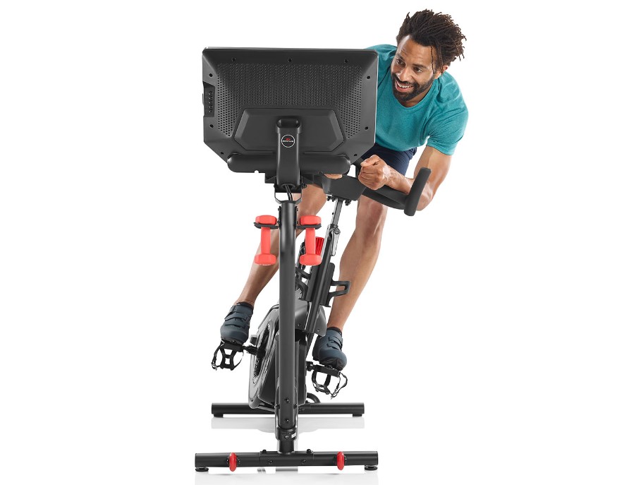 Front-on shot of a man riding a leaning Bowflex VeloCore exercise bike
