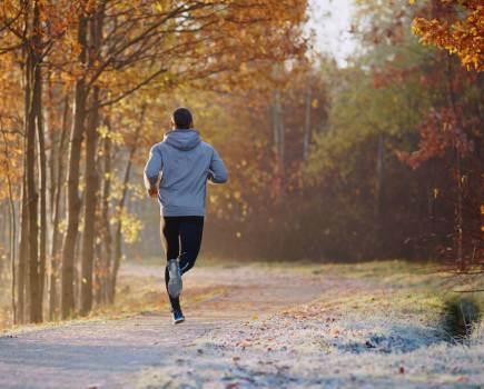 man running through a park on a cold Autumn day