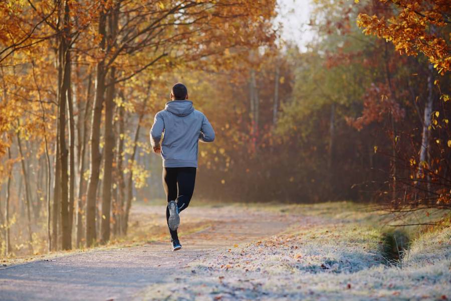 man running through a park on a cold Autumn day