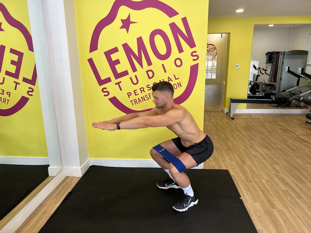 man performing banded squat as part of a resistance band workout for beginners