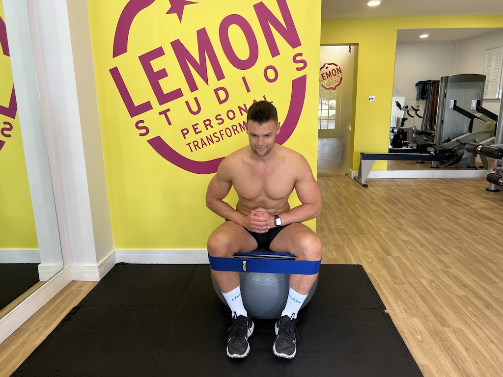 Man performing seated glute band abduction 