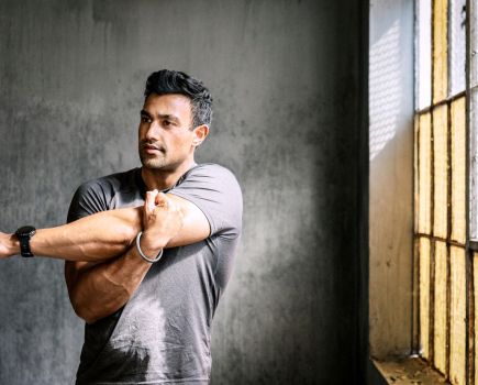 man stretching arms and shoulder in gym, testing out dynamic stretching vs static