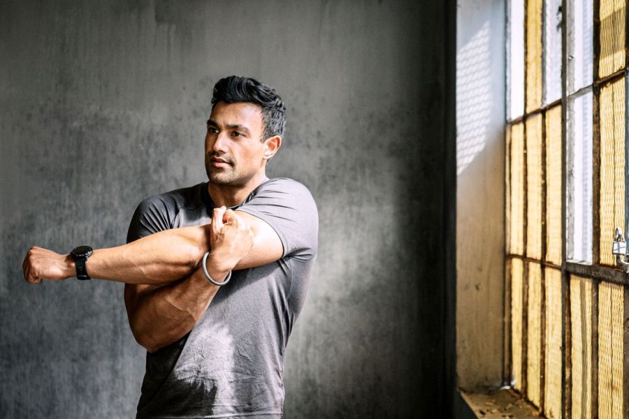 man stretching arms and shoulder in gym, testing out dynamic stretching vs static