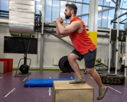 Man in a gym performing a box step-up