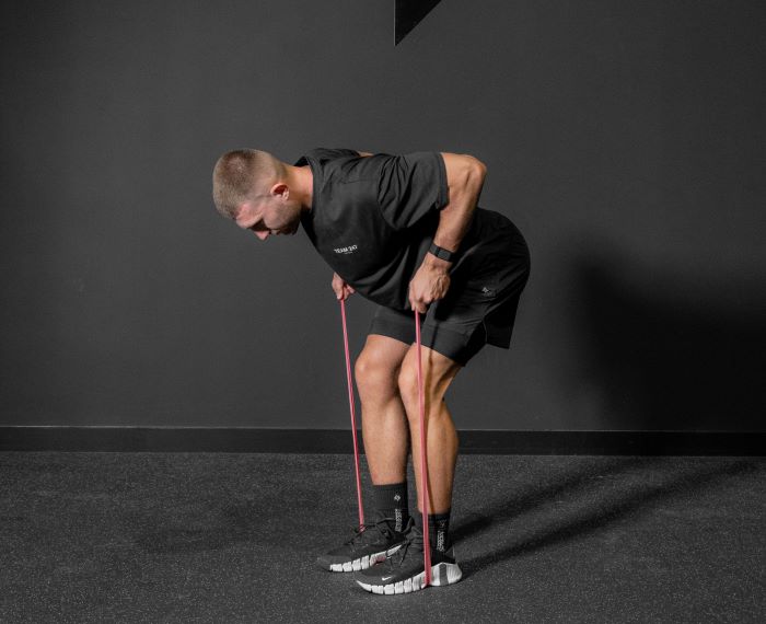 Man finishing movement of a resistance band bent over row