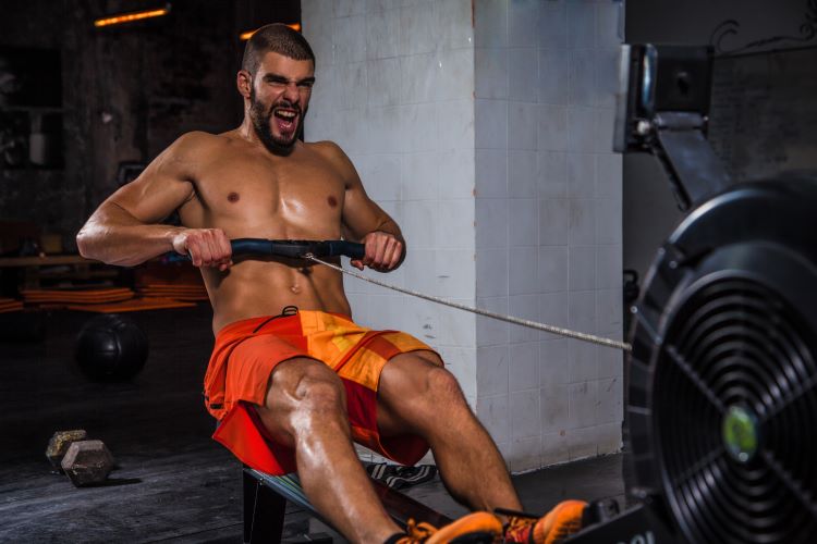 Man exercising hard on a rowing machine