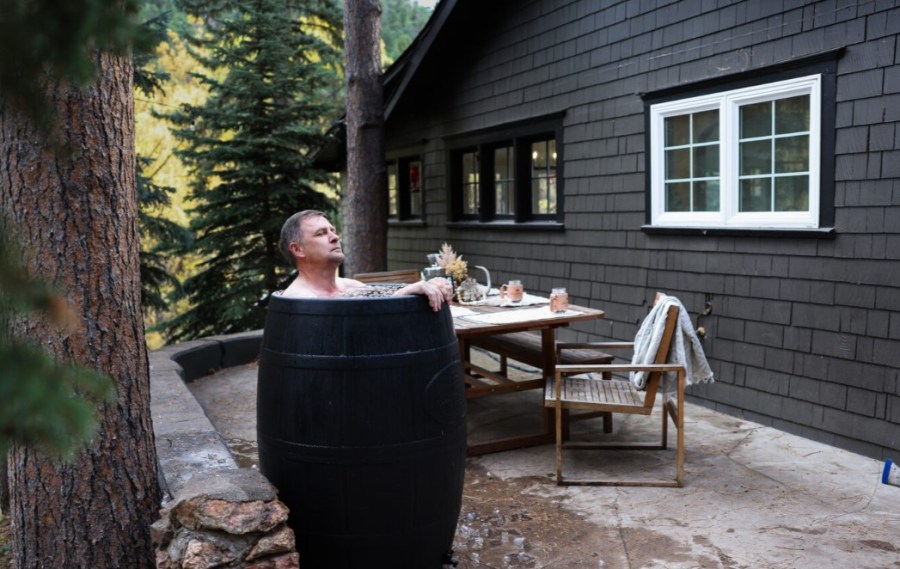 Man in an ice bath outside a cabin