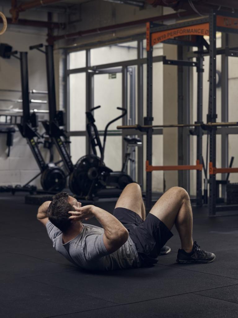 man demonstrates crunch exercise