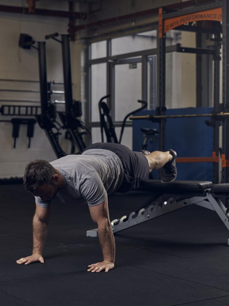 man demonstrates decline press up in gym