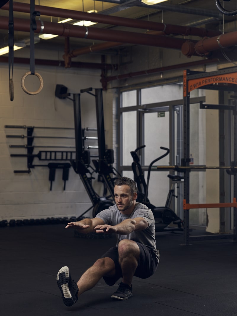 man demonstrates pistol squat, one of the best bodyweight exercises