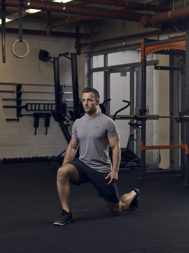 man shows how to do a reverse lunge, one of the best bodyweight exercises for building lower-body strength