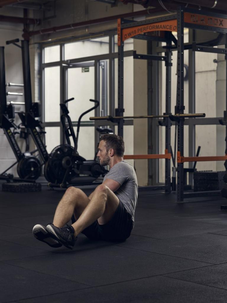 man demonstrates russian twist, one of the best bodyweight exercises for core strength