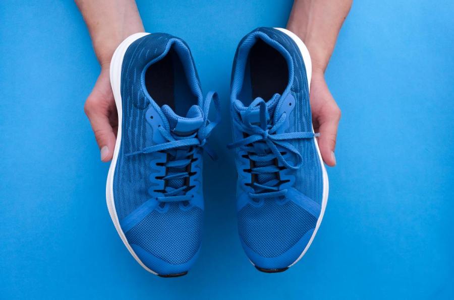 man holding pair of blue gym shoes