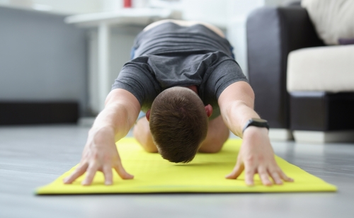 man performing back stretches at home