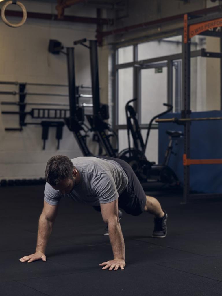 man performs spiderman press up in the gym