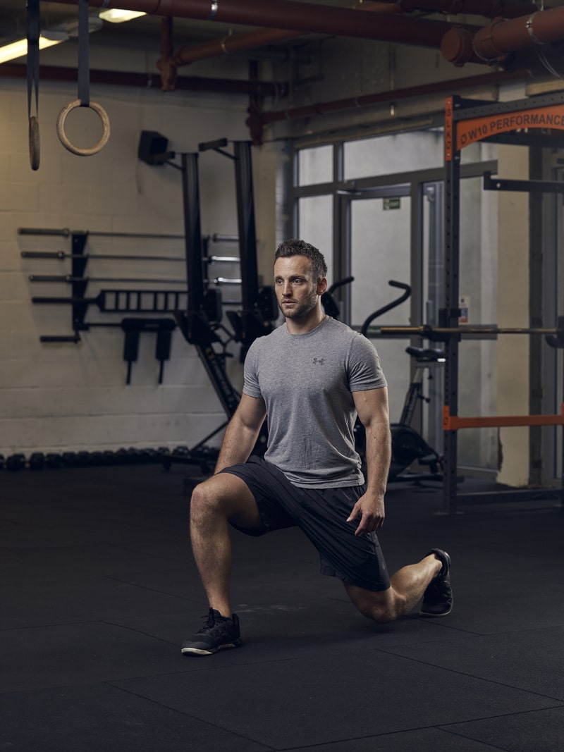 man demonstrates split squat in gym