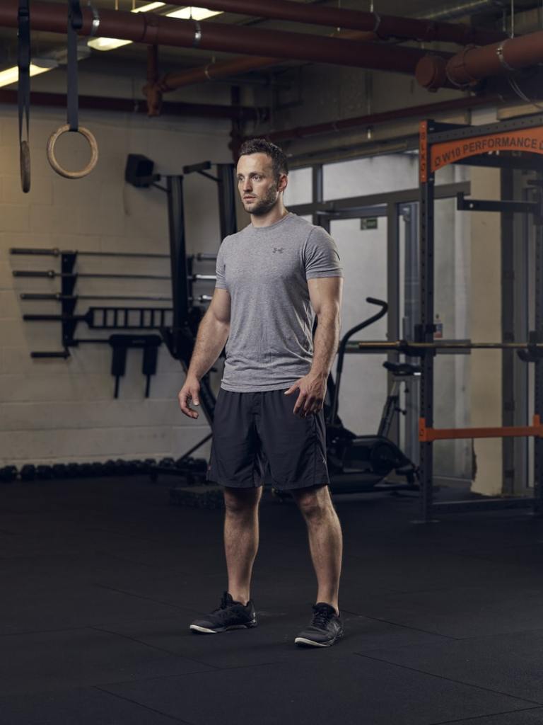 man demonstrates a basic squat, one of the best bodyweight exercises