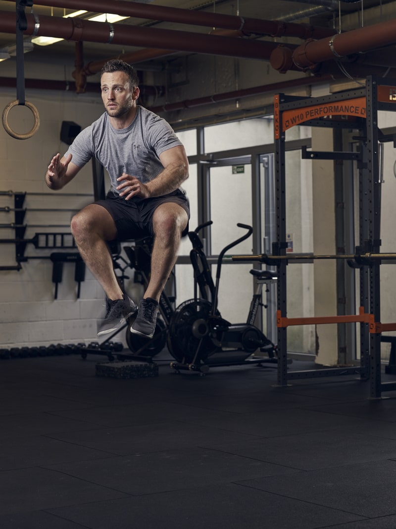 man performs tuck jump in gym, one of the best bodyweight exercises for full body strength