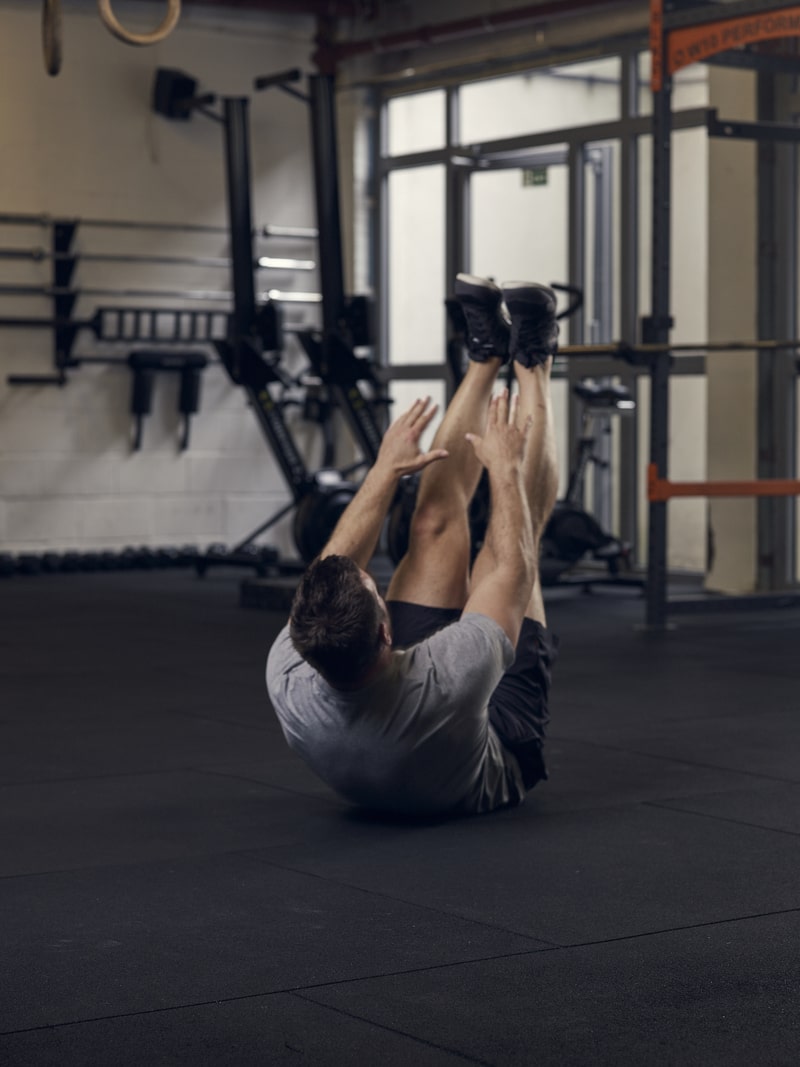 man demonstrates v-sit, one of the best bodyweight exercises for core strength