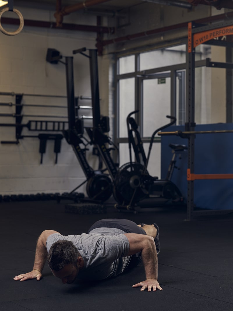 man lowers into wide press up position in gym