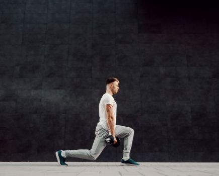 Side-on view of a man performing a dumbbell lunge