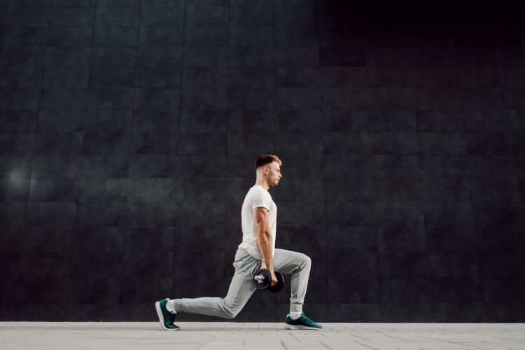 Side-on view of a man performing a dumbbell lunge