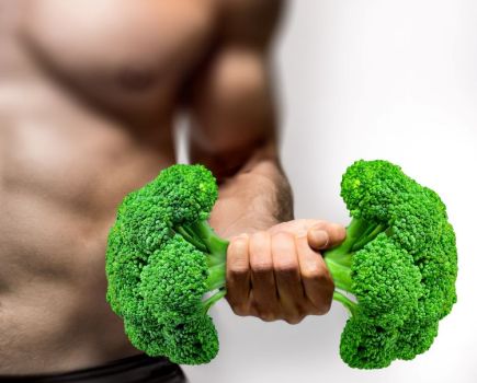 Close-up of a man holding broccoli like a dumbbell