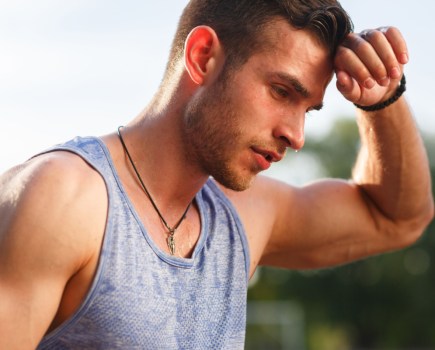 man wiping sweat from forehead after workout, learning how to measure sweat rate