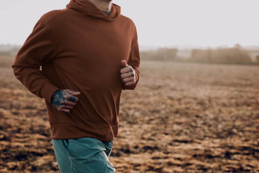 man jogging through countryside in hooded sweatshirt