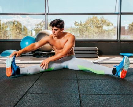 Man in a gym performs floor stretches