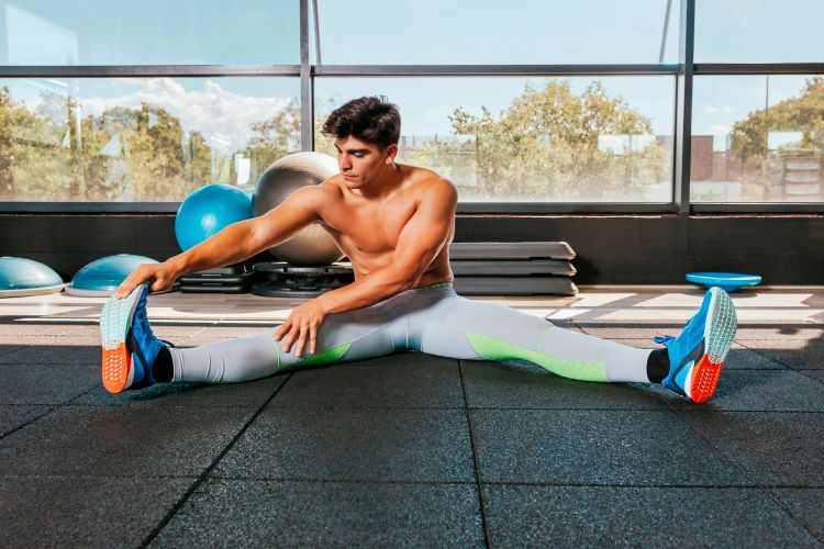 Man in a gym performs floor stretches