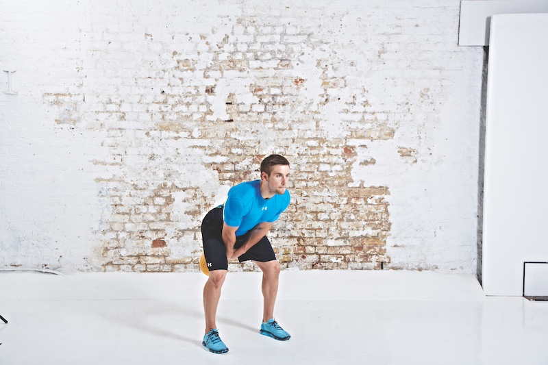 Man in blue top and black shorts performing kettlebell American swing