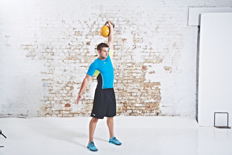 Man in blue top and black shorts performing kettlebell snatch