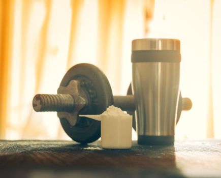 A serving of pre-workout powder, a shaker and dumbbell