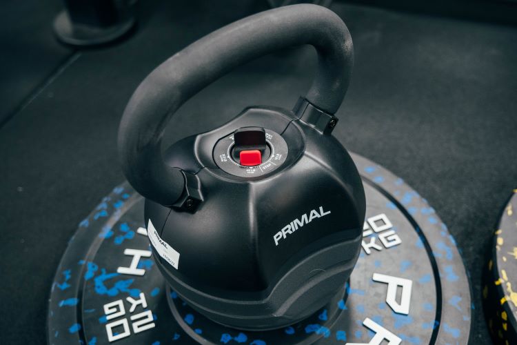 An adjustable kettlebell sitting on a weight plate