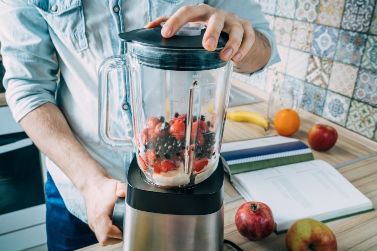 Close-up of a man using a food blender