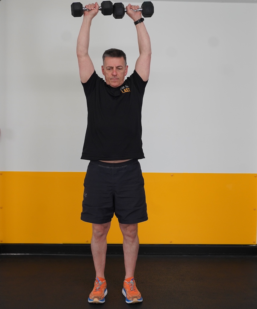 man performing overhead press with dumbbells to show how to strength train in your sixties