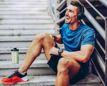 Handsome male jogger listening to music while taking break after