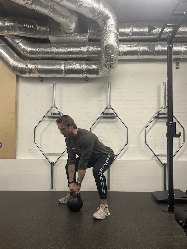 man in gym performing kettlebell deadlift exercise