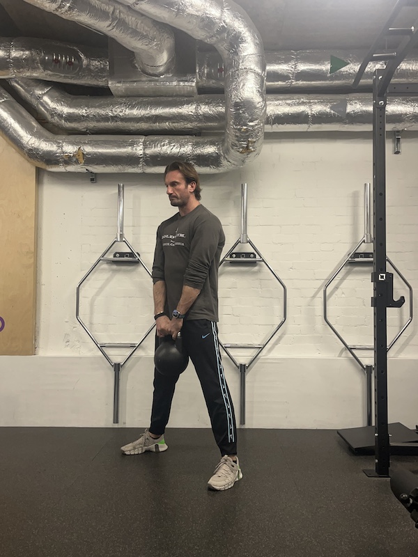 man in gym performing kettlebell deadlift exercise