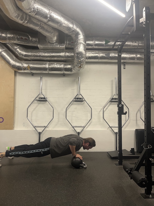 man performing kettlebell offset push-up in the gym