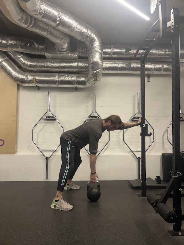 man performing kettlebell three-point row in the gym