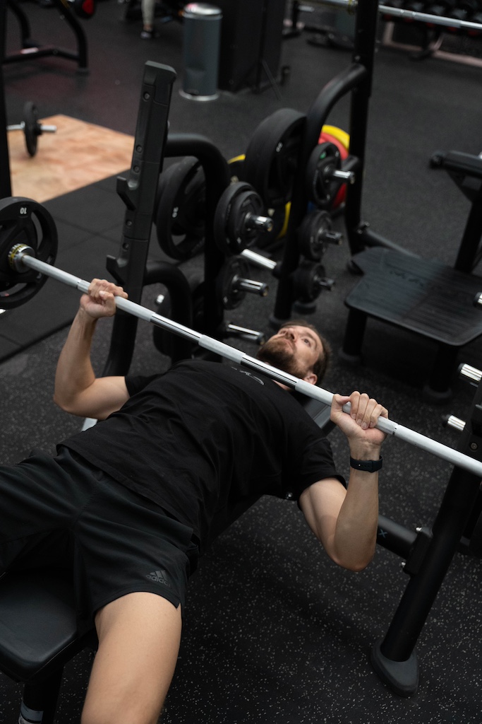 PT demonstrating how to perform a barbell bench press in a workout routine for beginners