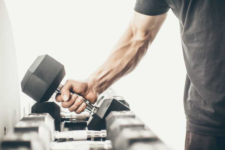 Close-up of a man lifting a dumbbell off a rack