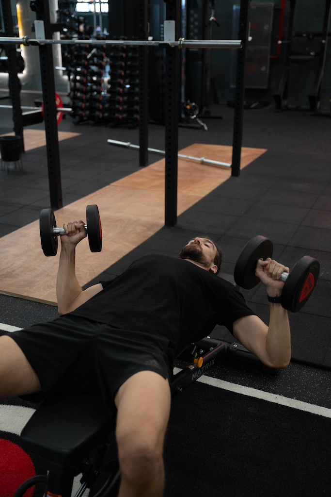 PT demonstrating how to perform a dumbbell bench press